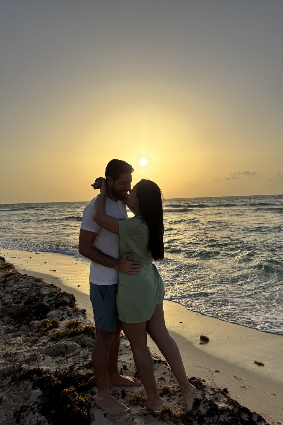 Um abraço na praia, com o sol baixo sobre o mar