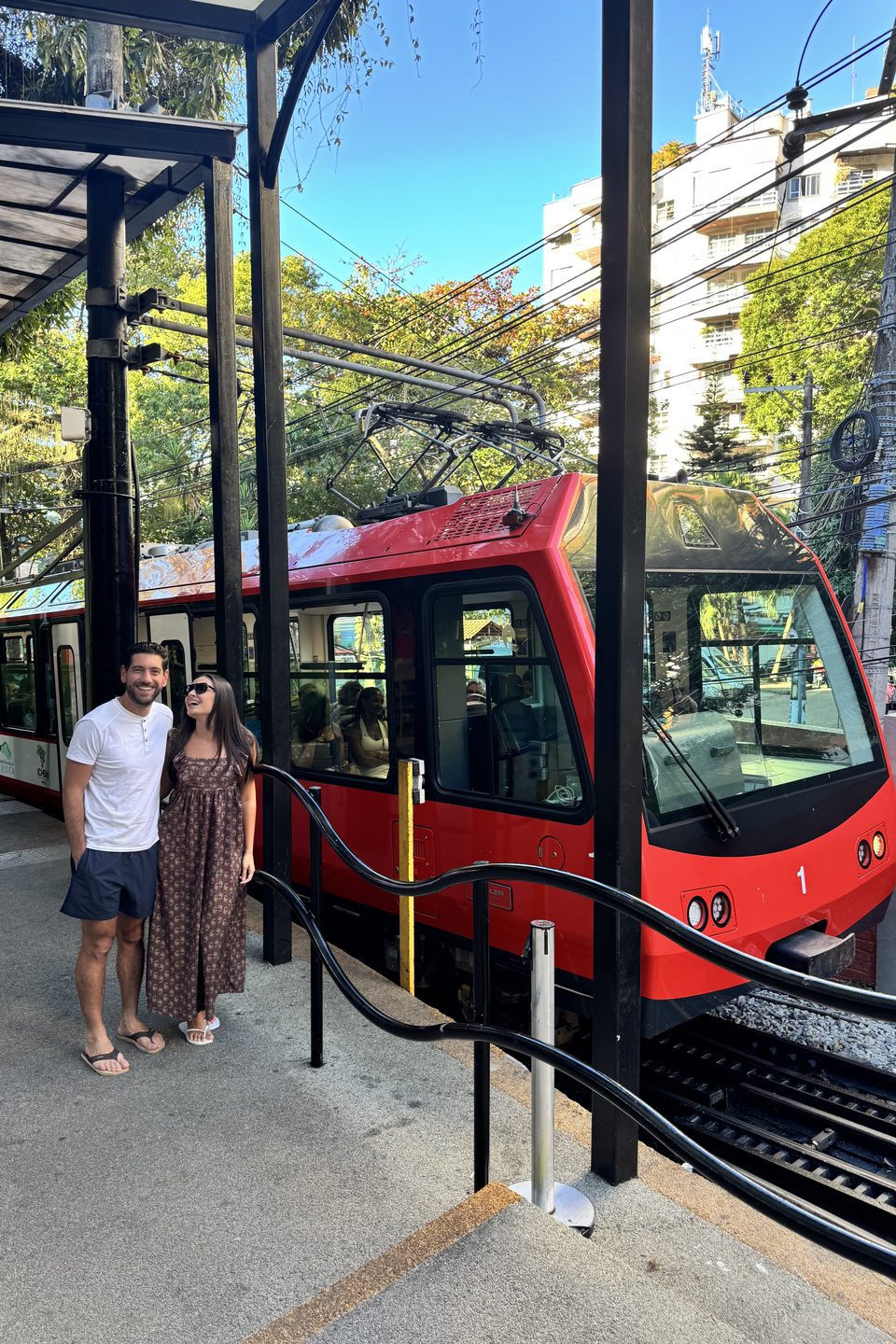 Os dois ao lado do bondinho vermelho