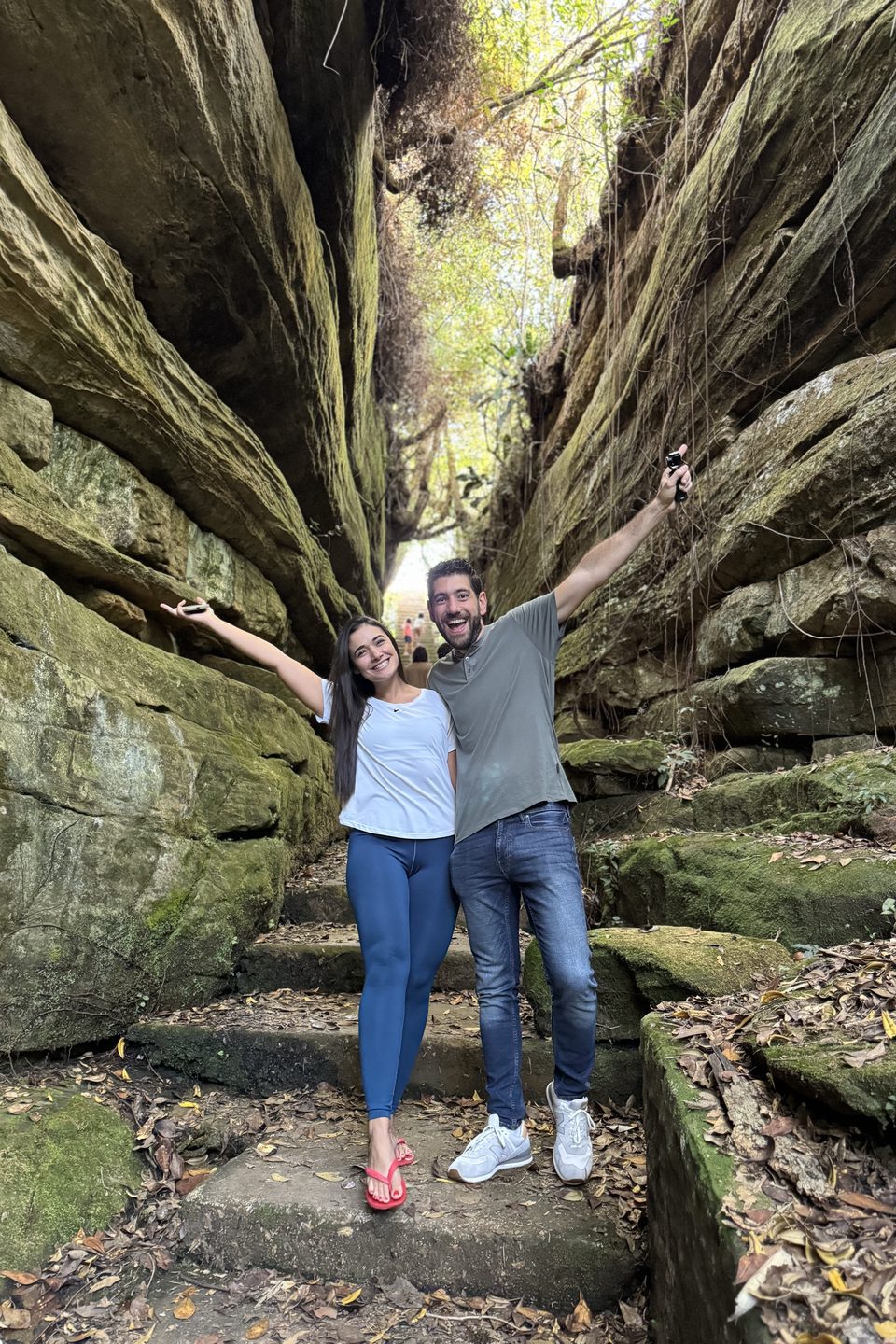 Os dois de braços abertos entre os paredões de pedra de Vila Velha