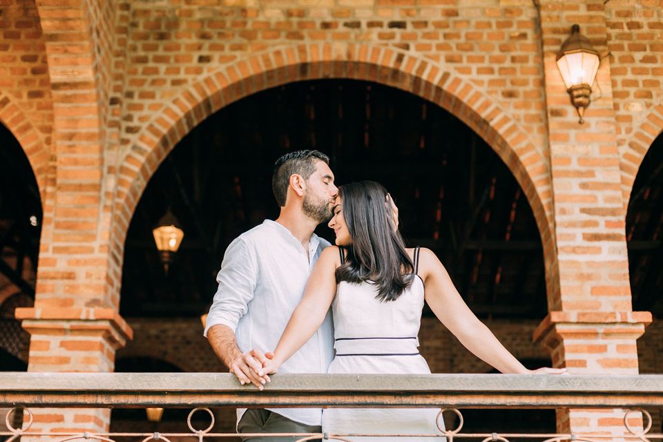 Os noivos se beijando na sacada de ferro, em plano aberto