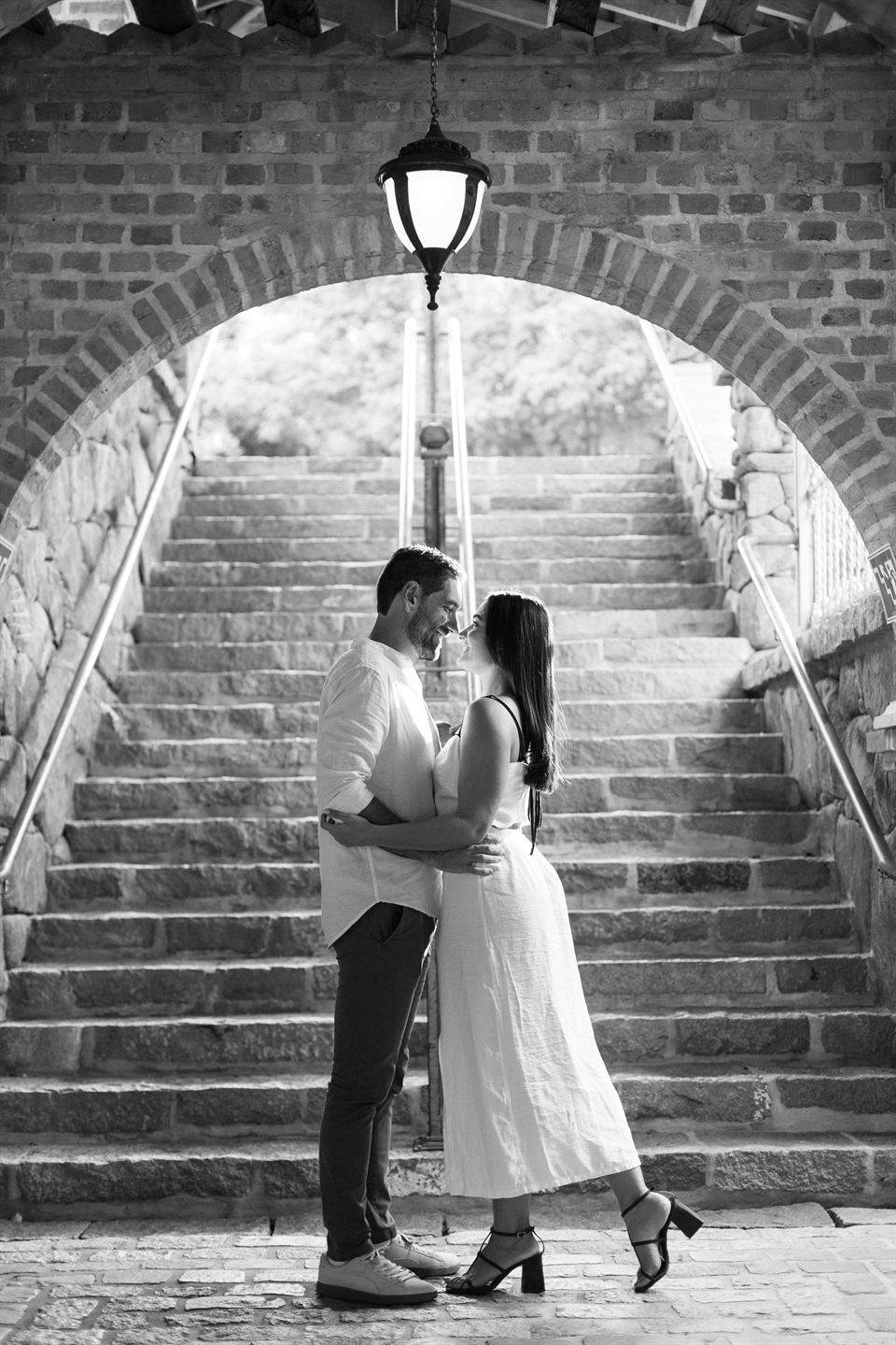 Ana e Renan se beijando na escadaria, em preto e branco